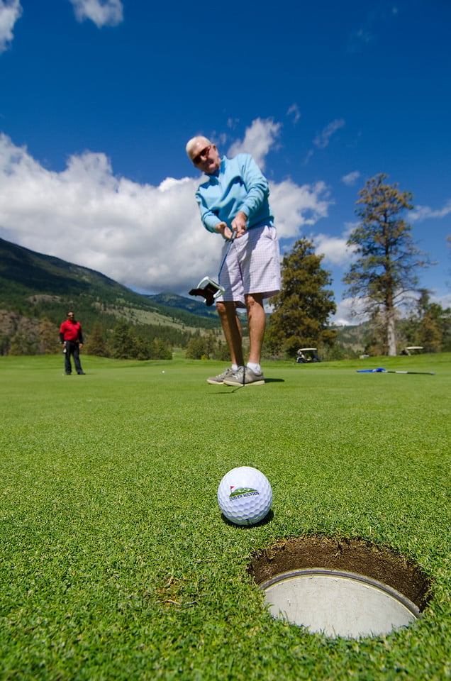 man putting golf ball toward hole