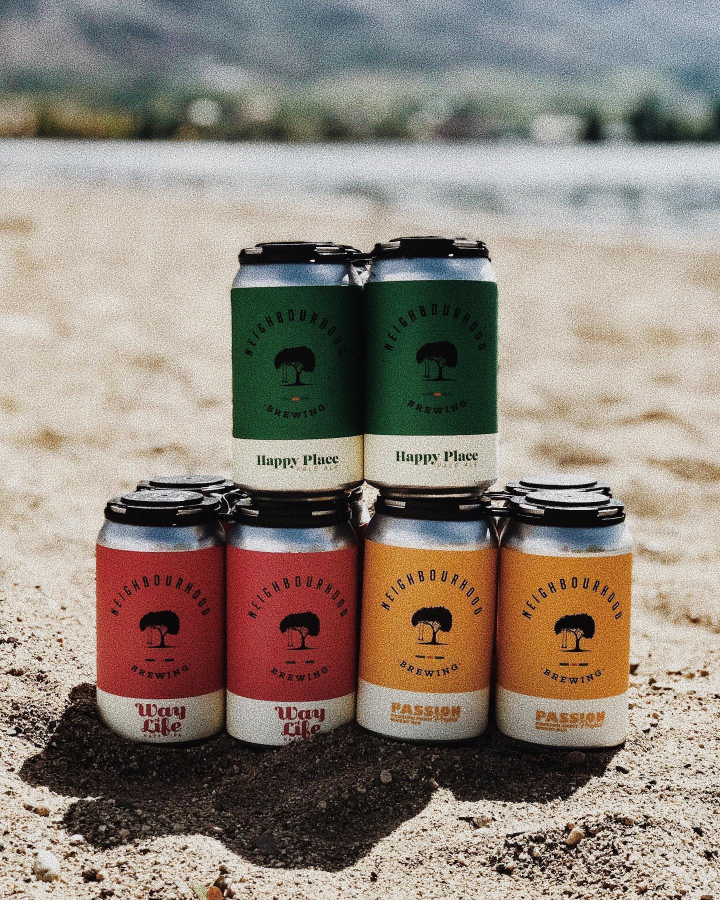 Neighbourhood Brewing beer cans stacked on beach